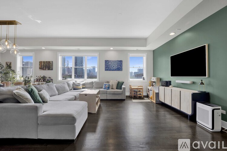 A modern living room with white furniture and a flat screen TV mounted on the wall.