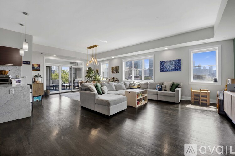 A spacious living room with a white sofa set and a wooden floor.