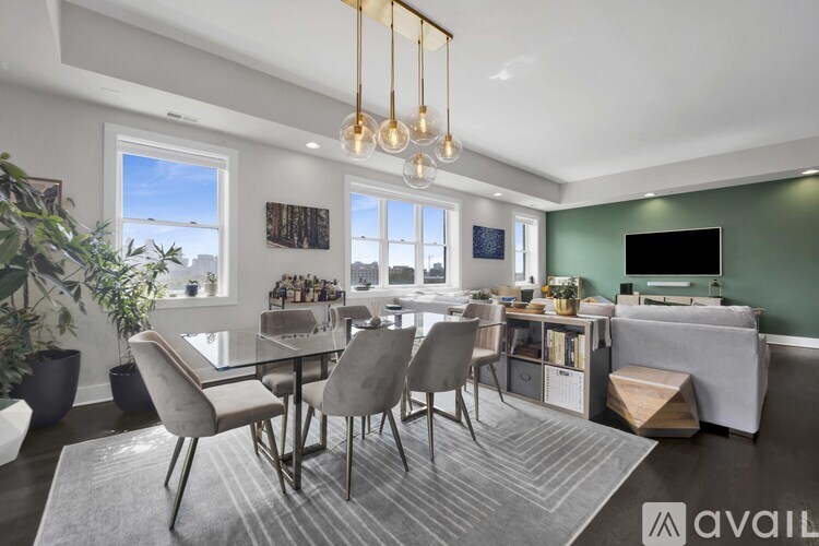 A modern dining room with a glass table and grey chairs.