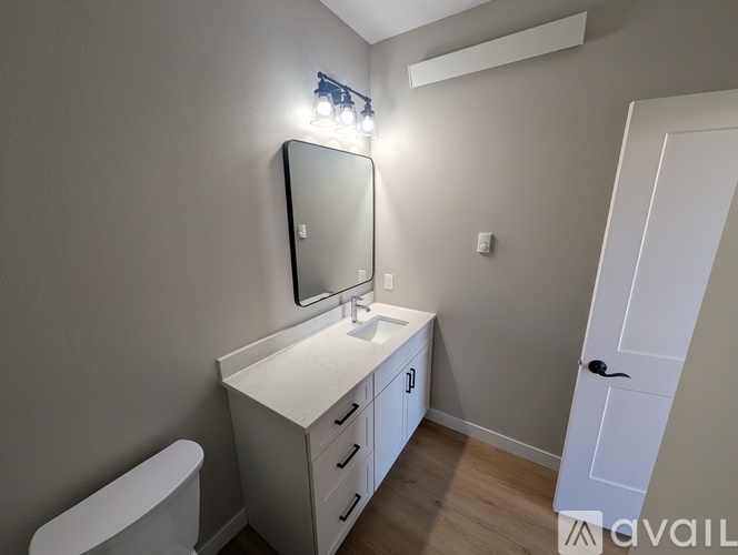 A bathroom with a white vanity, sink, and toilet.