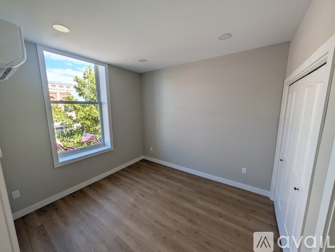 A room with a window showing a view of a building and trees.