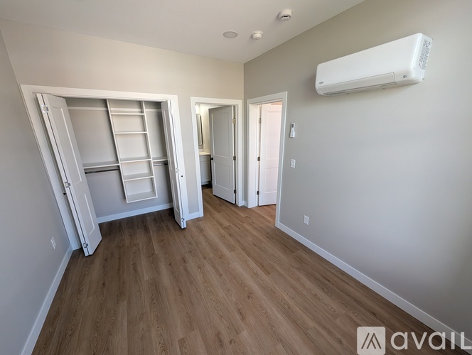 A room with a white wall and a white air conditioner unit mounted on it.