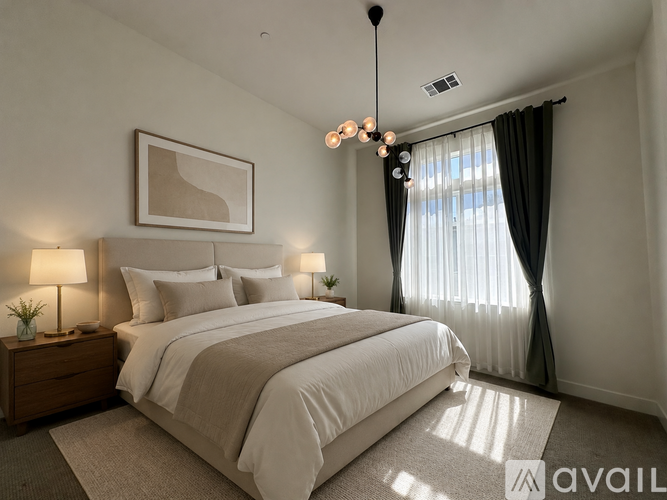 A well-lit bedroom with a large bed and a chandelier.
