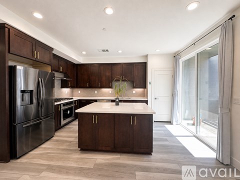 A modern kitchen with dark wood cabinets and stainless steel appliances.