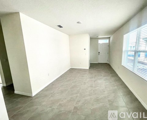 A spacious room with tiled flooring and white walls.
