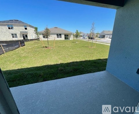 A view from a window looking out at a grassy area with houses in the distance.