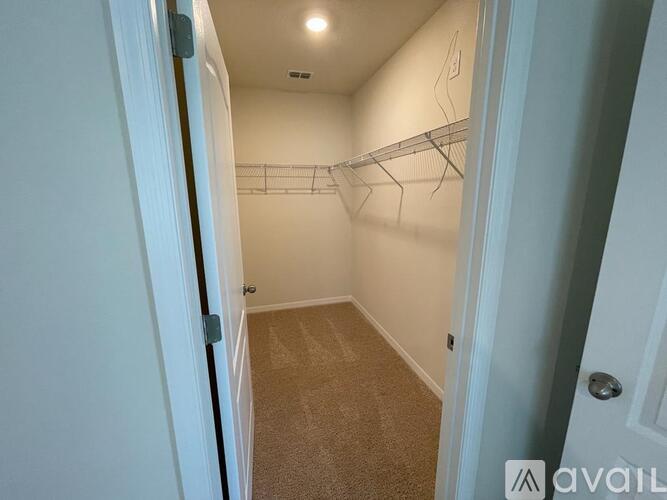 A white hallway with a carpeted floor and a door on the left.