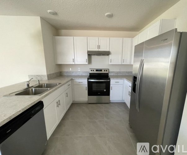 A kitchen with white cabinets and a stainless steel refrigerator.
