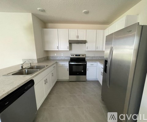 A kitchen with white cabinets and a stainless steel refrigerator.