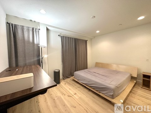 A bedroom with a bed, nightstand, and window with curtains.