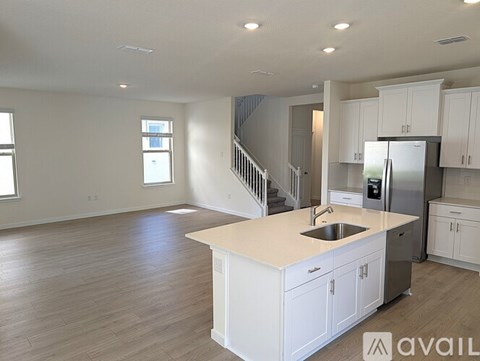 A spacious kitchen with white cabinets and a stainless steel refrigerator.