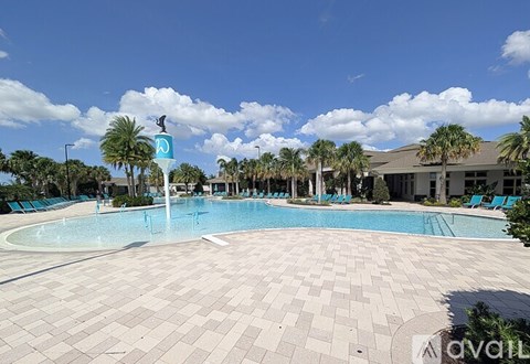 A large outdoor swimming pool surrounded by palm trees and lounge chairs.