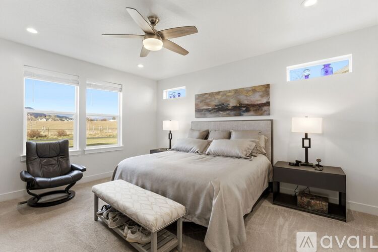 A bedroom with a bed, chair, and a ceiling fan.