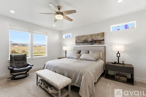 A bedroom with a bed, chair, and a ceiling fan.