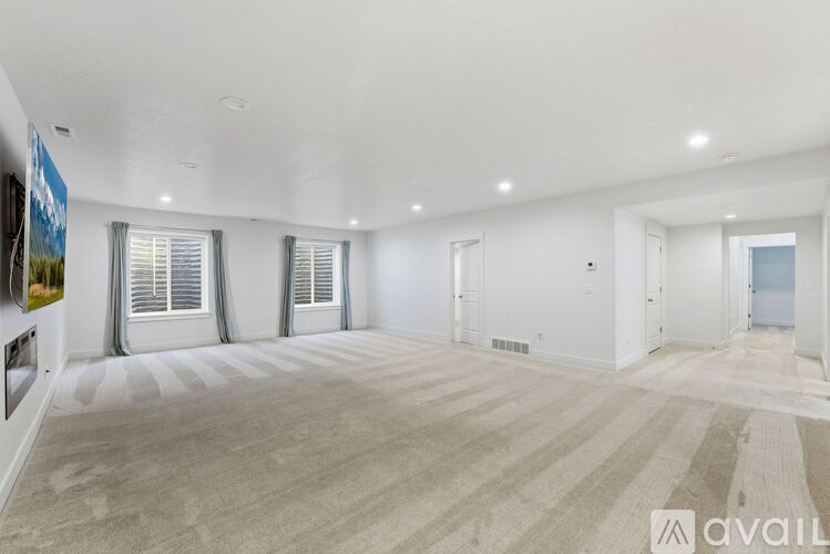 A spacious room with beige carpeting and white walls is available for rent.
