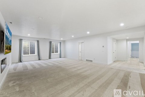 A spacious room with beige carpeting and white walls is available for rent.