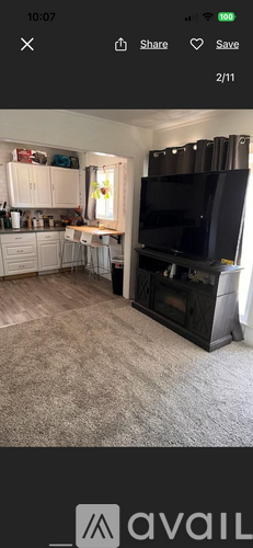 A living room with a large television and a dining table.