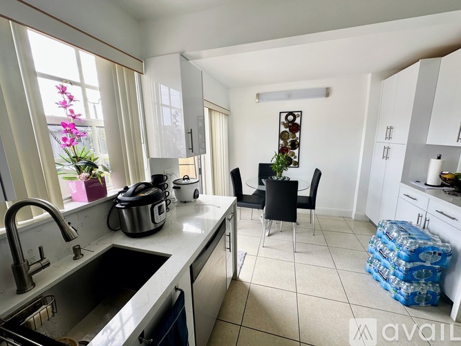 A kitchen with a sink, stove, and a dining table with chairs.