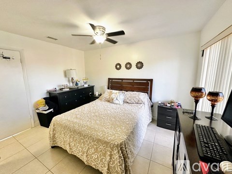 A bedroom with a bed, dresser, and ceiling fan.