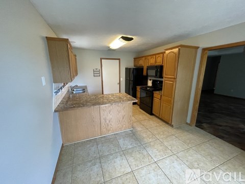 A kitchen with a black refrigerator and wooden cabinets.