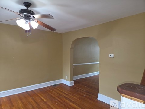 A room with a ceiling fan and wooden floors.