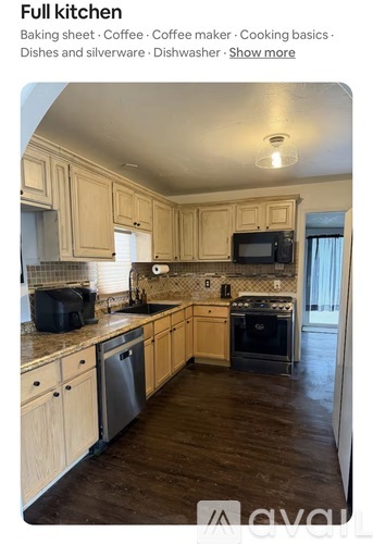 A kitchen with wooden cabinets and a black dishwasher.