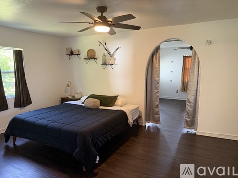 A bedroom with a bed, a ceiling fan, and a mirror.