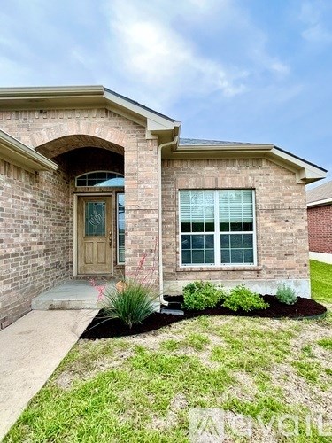 A brick house with a brown door and a window with white blinds.