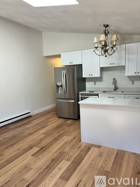 A kitchen with a refrigerator, cabinets, and a chandelier.
