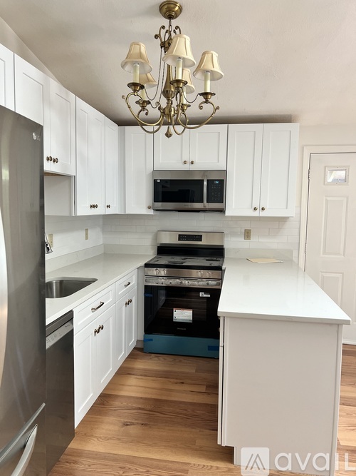 A kitchen with white cabinets and a chandelier.