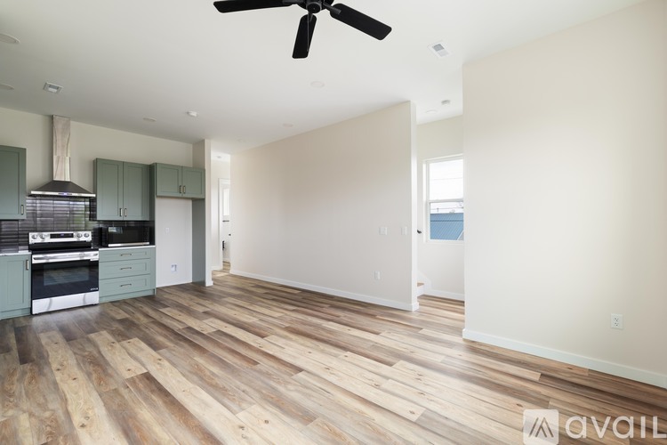 A spacious room with a ceiling fan and wooden flooring.