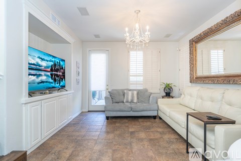 A living room with a grey couch and a large painting on the wall.