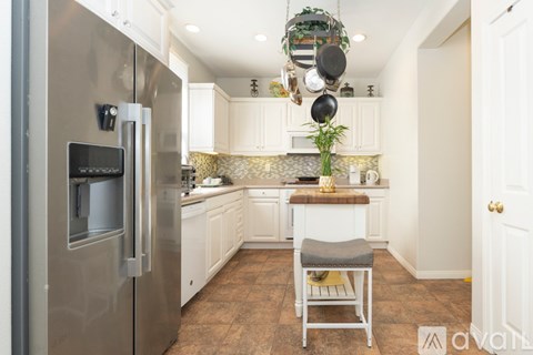 A kitchen with a stainless steel refrigerator and white cabinets.