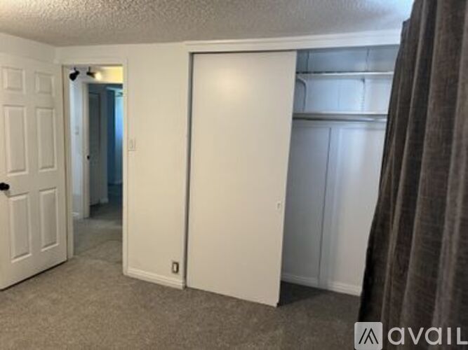 A bedroom with a white door and a carpeted floor.