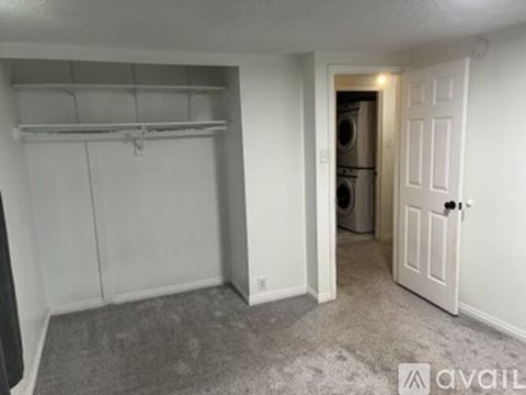 A small, empty room with a washer and dryer in the doorway.