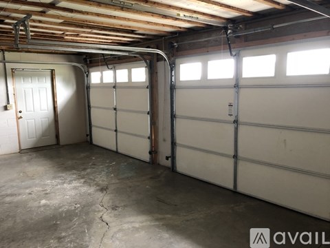 A spacious garage with two white doors and a cracked floor.