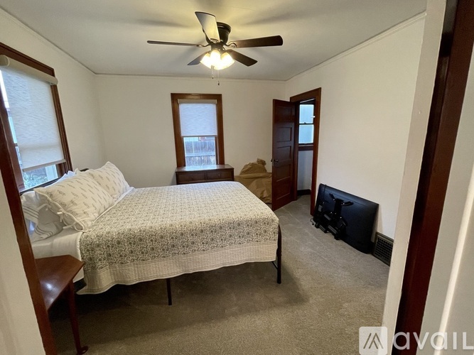 A bedroom with a bed, a ceiling fan, and a window.