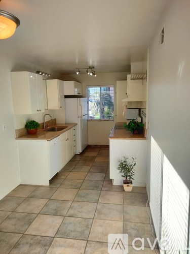A kitchen with white cabinets and a tiled floor.
