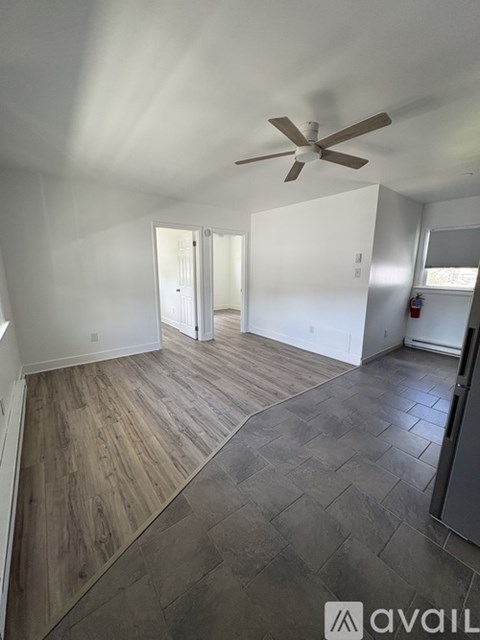 A room with a ceiling fan and wooden flooring.