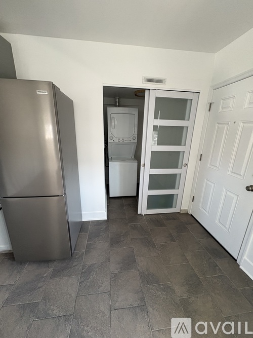 A kitchen with a stainless steel refrigerator and a white door.