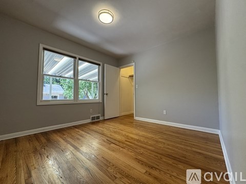 A room with wooden flooring and a window overlooking a building.