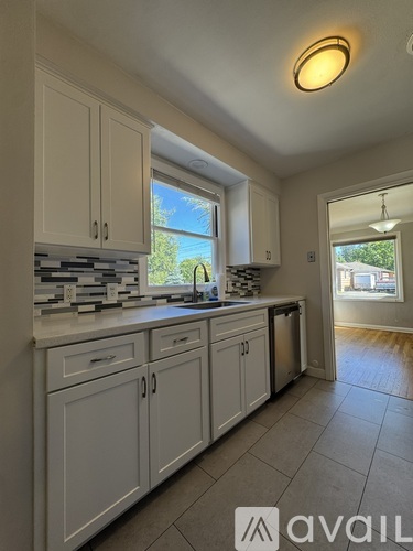 A kitchen with white cabinets and a window overlooking a tree.