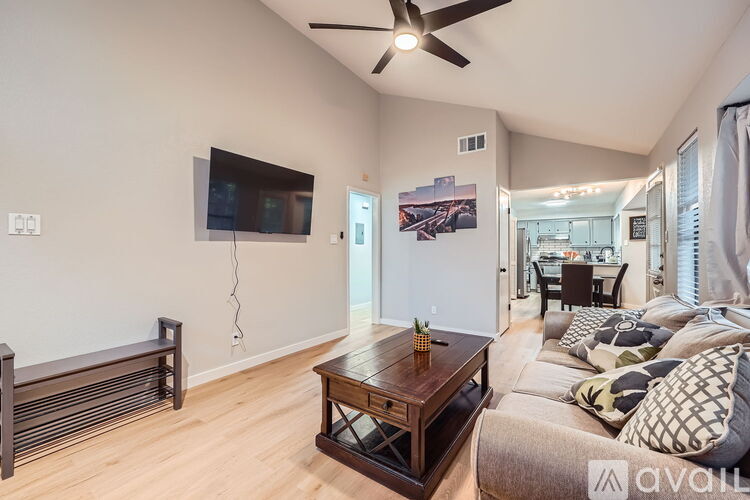 A living room with a wooden coffee table and a flat screen TV mounted on the wall.