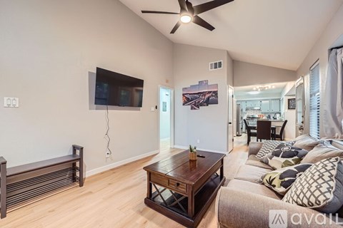 A living room with a wooden coffee table and a flat screen TV mounted on the wall.