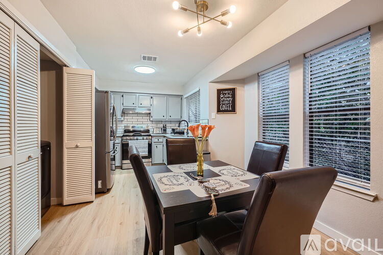 A dining room with a table set for two and a chandelier hanging from the ceiling.