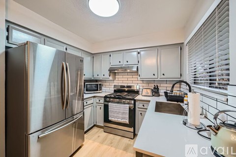 A kitchen with a stainless steel refrigerator and a white countertop.