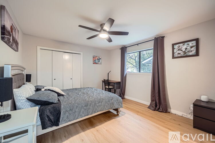 A bedroom with a bed, a ceiling fan, and a window with curtains.
