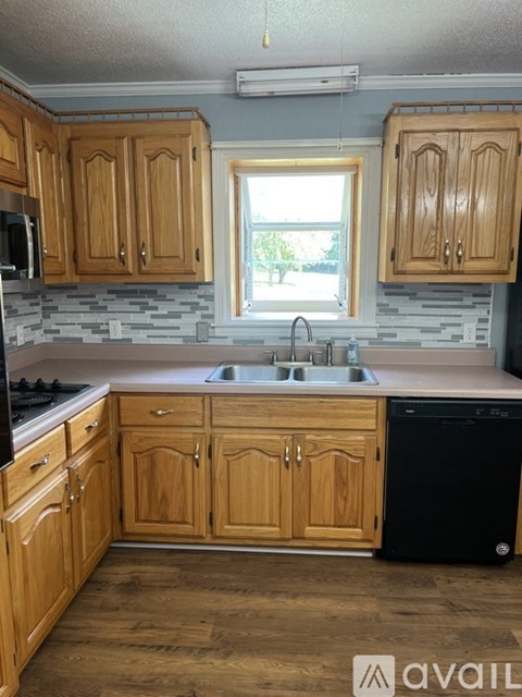 A kitchen with wooden cabinets and a black dishwasher.