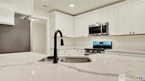 A modern kitchen with white cabinets and a black faucet.
