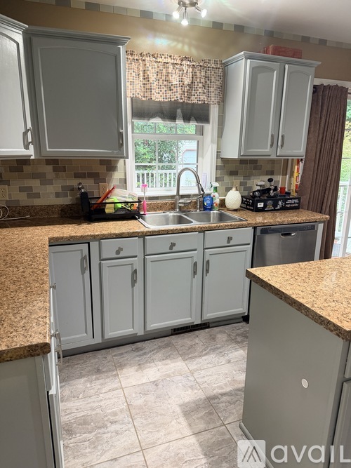 A kitchen with granite countertops and grey cabinets.